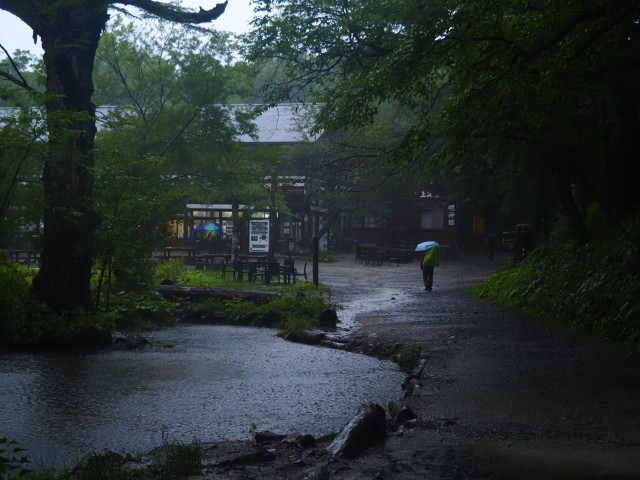 雨に煙る登山口を歩く人