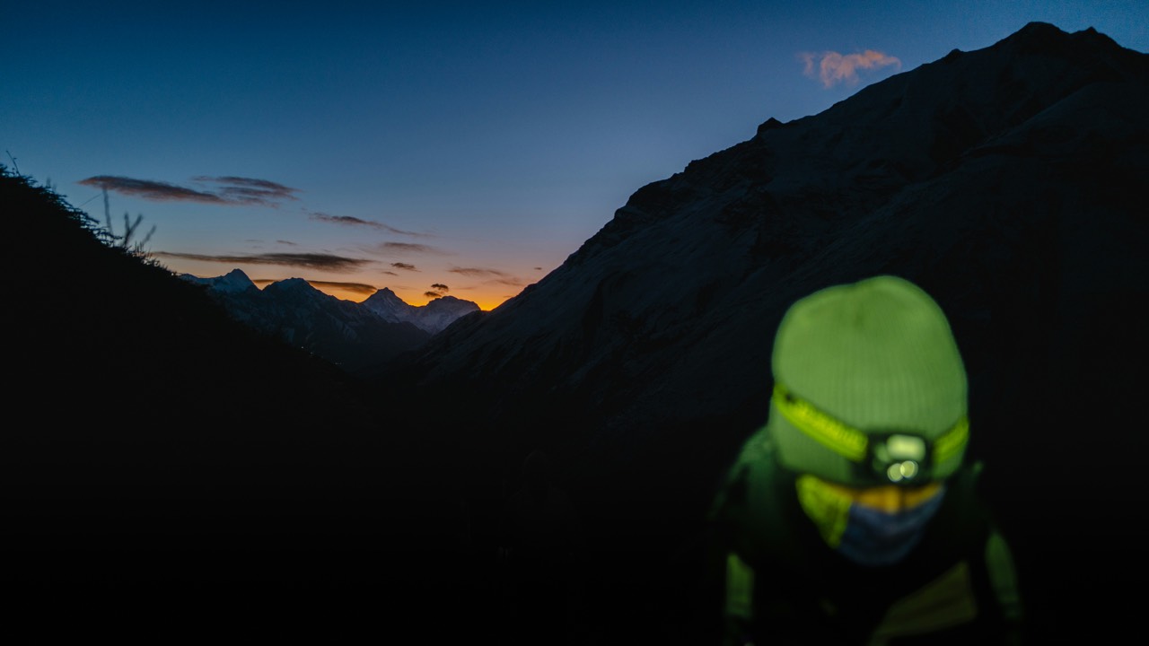 夕暮れの山でヘッドライトを点けて歩く登山者